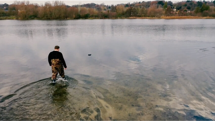 A picture of a man wading into a lake to install a WATR device