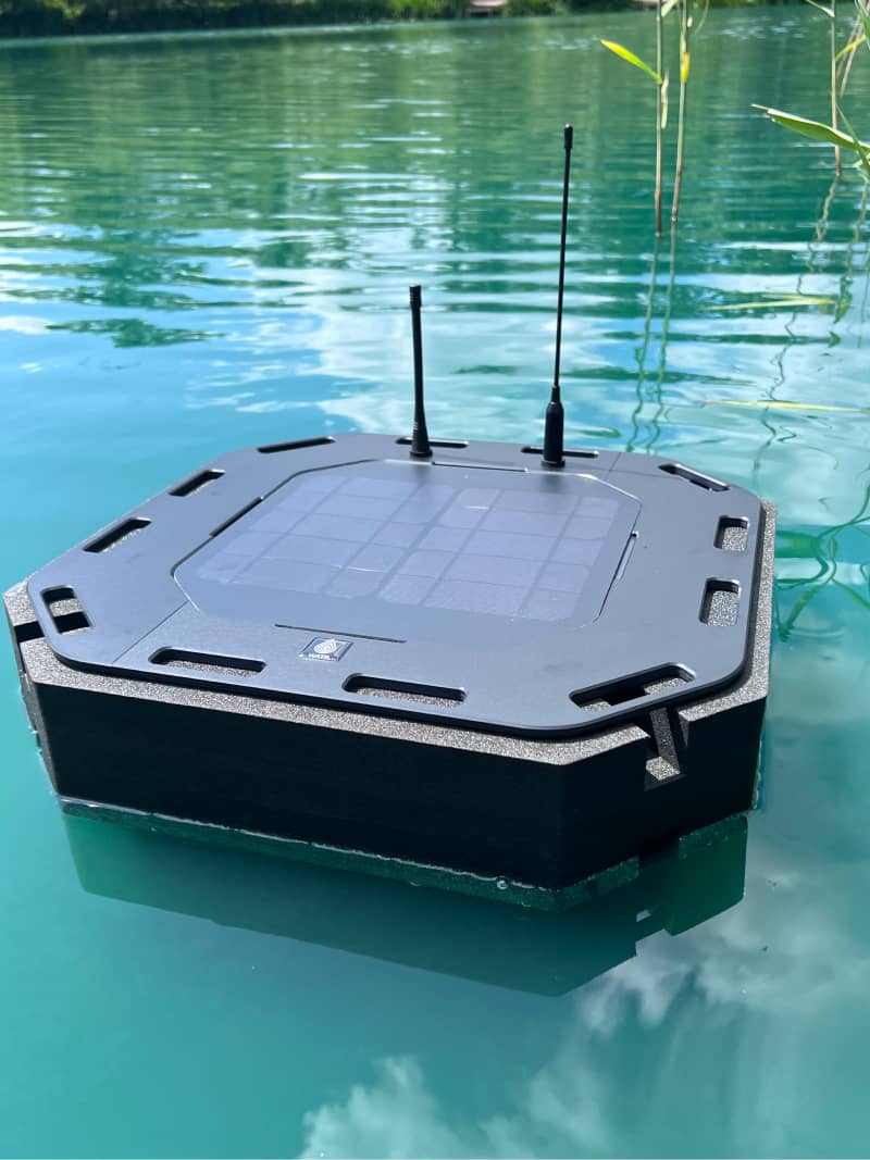 Photo of the WATR Pro unit sitting in a lake, floating so that the solar panel sits above the water